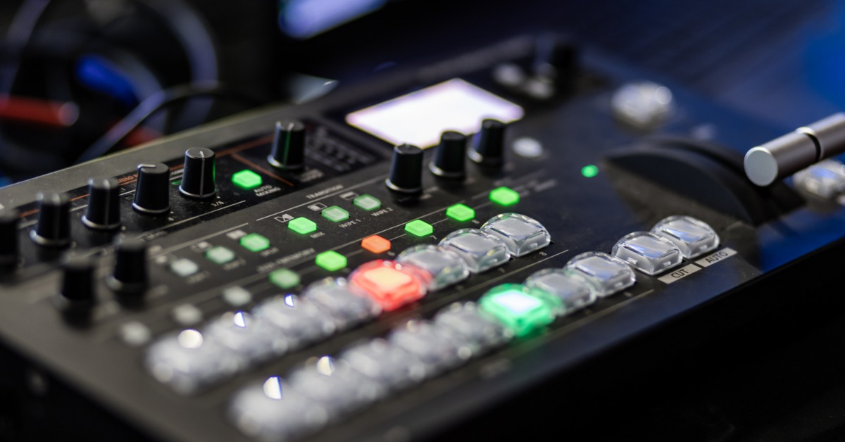 A control panel with knobs and buttons used for audio mixing, shown in close-up with various controls visible.